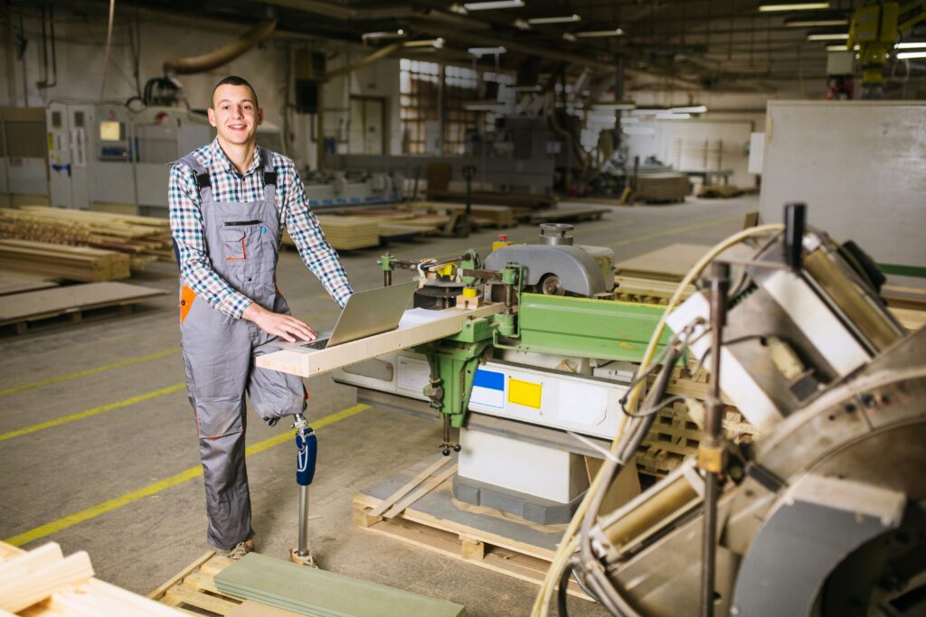 Jeune charpentier avec une prothèse de jambe dans un atelier